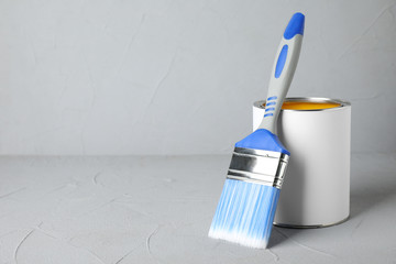 Can of paint and brush on grey table. Space for text