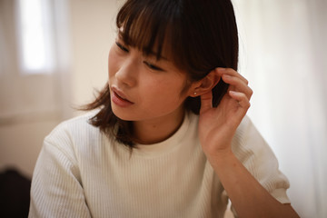 耳に違和感を感じる女性