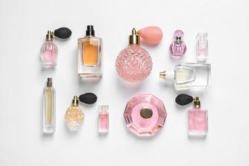 Different luxury perfume bottles on white background, top view