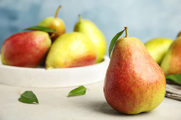 Ripe juicy pears on white stone table against blue background, closeup. Space for text