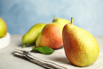 Ripe juicy pears on grey stone table against blue background, closeup. Space for text