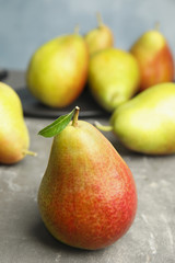 Ripe juicy pears on grey stone table against blue background
