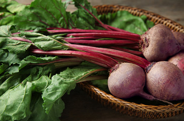 Wicker basket with bunch of fresh beets on table, closeup