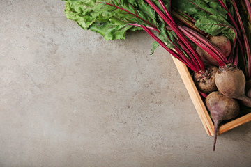 Wooden crate with fresh beets on grey table, top view. Space for text