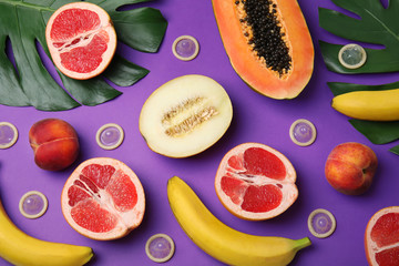 Flat lay composition with condoms and exotic fruits on purple background. Erotic concept