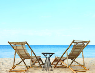Empty wooden sunbeds and beach accessories on sandy shore