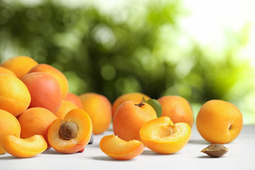 Delicious ripe sweet apricots on white table against blurred background, space for text