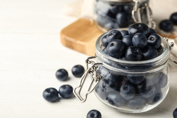 Jar of fresh acai berries on white wooden table, closeup view. Space for text