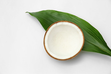 Half of fresh coconut and palm leaf on white background, top view