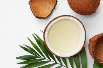 Composition with drink in half of coconut and palm leaf on white background, top view