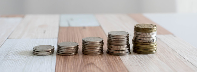 Savings, increasing columns of coins isolated on white background and wooden table