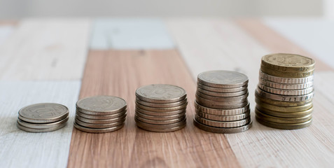 Savings, increasing columns of coins isolated on white background and wooden table