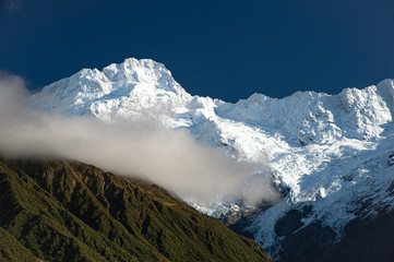 Gorgeous white snow covered top of Aoraki Mount Cook with part of beautiful mist  blue sky background in New Zealand.
