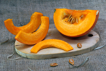 slices of pumpkin on cutting board isolated on burlap background