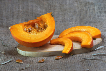 slices of pumpkin on cutting board isolated on burlap background
