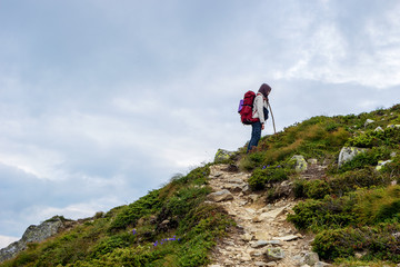 Young girl with red backpack trekking in high mountain route.