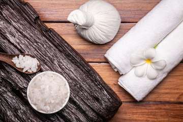 Spa aromatic sea salts, and herbal massage ball on wooden background.