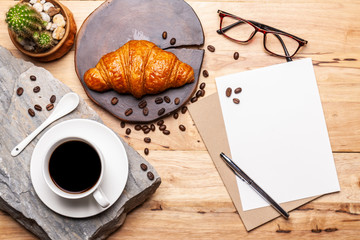 Coffee with coffee beanand and Croissant note  pad  on wooden table