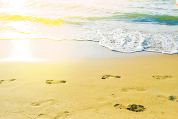 Female footprints on the beach. Sunlight on beach sands and sea.