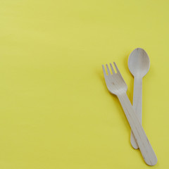 Bamboo wooden spoons and forks on yellow background with space for text. Eco friendly kitchen utensils. Ecological concept.