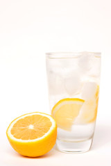 Glass of water on ice with lemon slice isolated on white background; popular morning healthy beverage