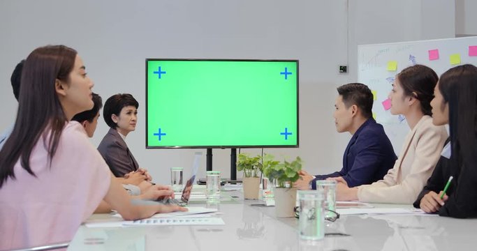 Group of Business People looking to monitor in meeting room. Green screen background inside monitor. Business concept.