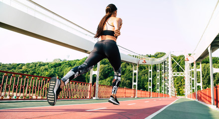 Faster than wind. Back view full length photo of jogging young sporty woman on city bridge.