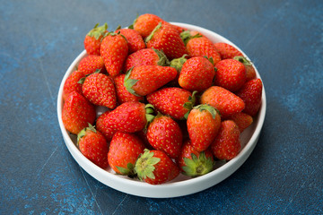 Fresh red strawberries on a blue concrete background.