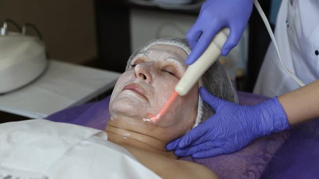 girl at the beautician. Cleaning the face. Darsonvalization.