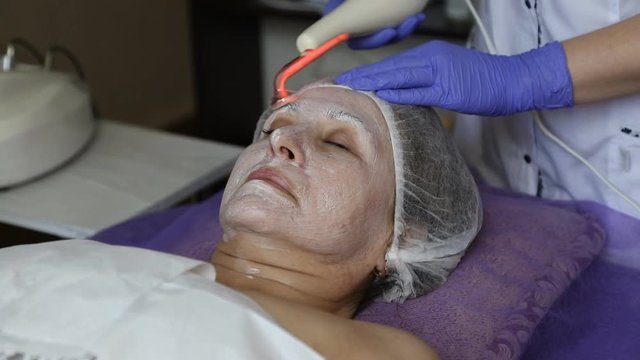 girl at the beautician. Cleaning the face. Darsonvalization.