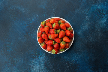 Fresh red strawberries on a blue concrete background. Copy space