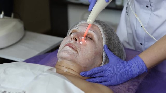girl at the beautician. Cleaning the face. Darsonvalization.
