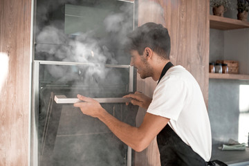 emotional young man standing near broken oven