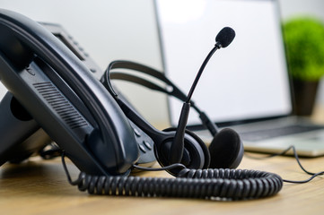 Close up IP telephone with head set on wood table and blurred of laptop computer on background