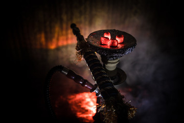 Hookah hot coals on shisha bowl on dark foggy background. Stylish oriental shisha.