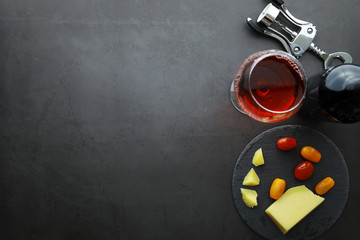 Wine glass and black wine bottle. Nuts cheese and tomatoes for snack.