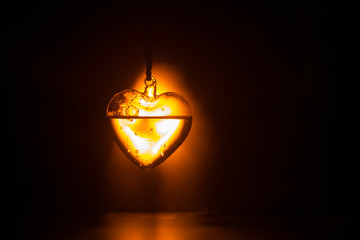 Valentines Day Concept. Glass transparent heart on dark. Crystal heart in the dark, glass heart glows, glass painting, black background