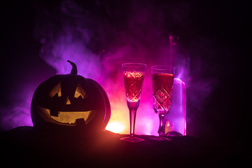 Two glasses of wine and bottle with Halloween - old jack-o-lantern on dark toned foggy background....
