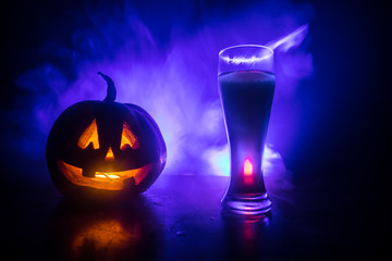 Glass of cold light beer with pumpkin on a wood background for Halloween. Glass of fresh beer and...