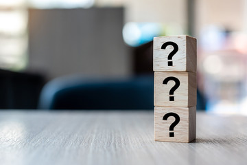 Questions Mark ( ? ) word with wooden cube block on table background. FAQ( frequency asked...