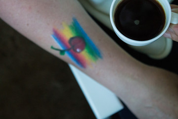 Rainbow and cherry painted face painting on a human hand