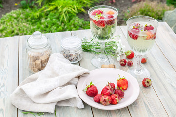 Champagne wine and strawberries. Summer food composition on a wooden table.