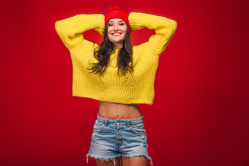 Girl in yellow sweater and hat on red background