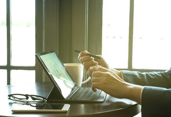 businessman point the stylus pen to tablet for analysis graph visualization at coffee shop