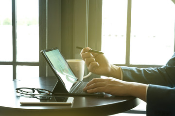businessman point the stylus pen to tablet for analysis graph visualization at coffee shop