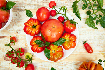 Mix of tomatoes background. Beautiful juicy organic red tomatoes on white wooden table background. Clean eating concept. Copy space, flat lay..