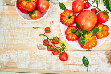 Mix of tomatoes background. Beautiful juicy organic red tomatoes on white wooden table background. Clean eating concept. Copy space, flat lay..