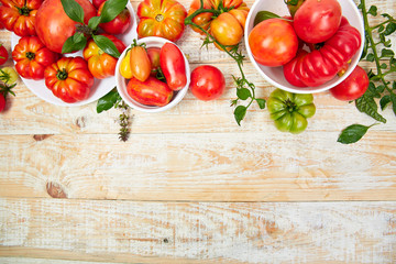 Mix of tomatoes background. Beautiful juicy organic red tomatoes on white wooden table background. Clean eating concept. Copy space, flat lay..