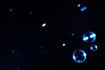 Soap bubbles of blue color on a dark background