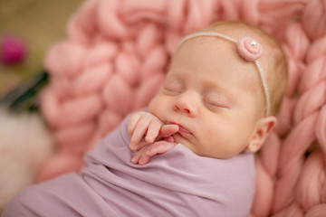 Perfect newborn baby girl in pink blanket in a wicker basket decorated with beautiful spring pink tulips